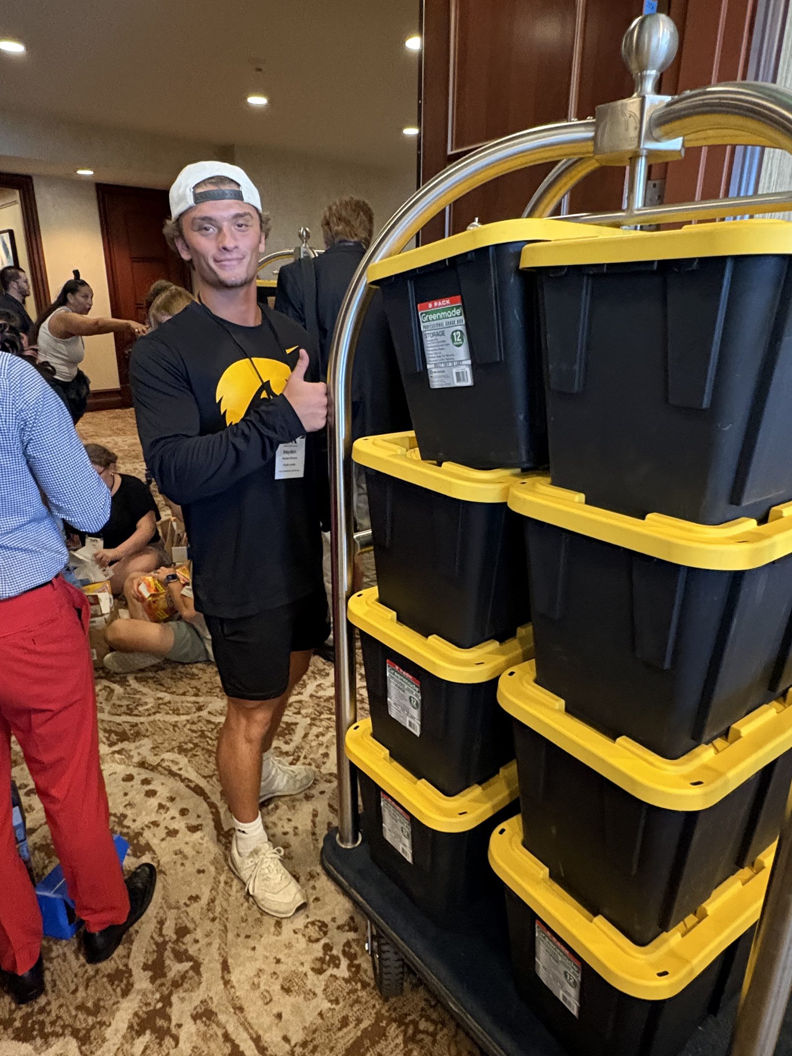 Volunteer giving a thumbs up next to stacked bins of packed bags
