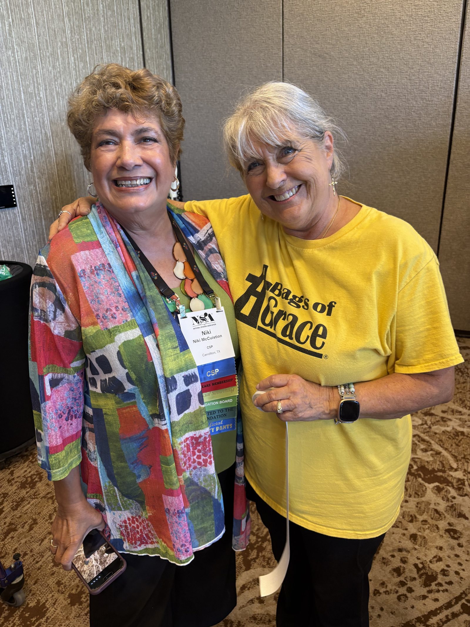 Two women embracing, one wearing a Bags of Grace shirt